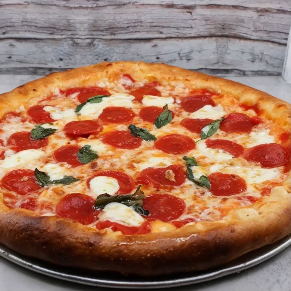 A Partners II Pizza pepperoni pizza with fresh mozzarella and basil on a metal pan.